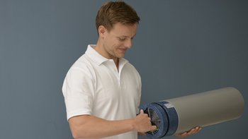 Ein Mechatroniker hält ein großes Filterrohr in den Händen.