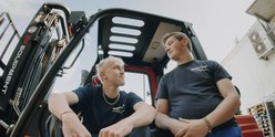 Die beiden Jungs im Gabelstapler scheinen sich gut zu verstehen, während sie in die Ferne blicken und die Sonne genießen.