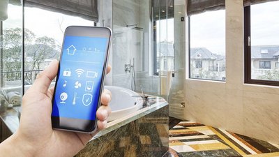 Badezimmer mit einer Hand die ein Smartphone hält, die eine Steuerung einer Lueftung-Klima-App zeigt.